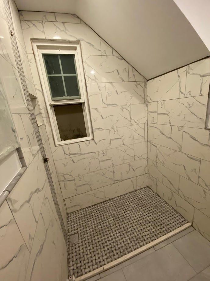 A bathroom with a walk in shower and a window.