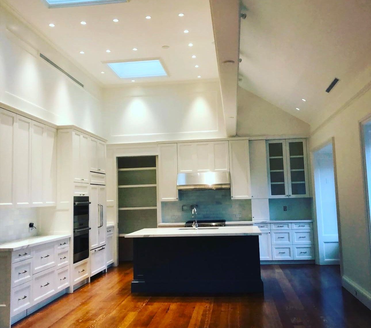 An empty kitchen with white cabinets and hardwood floors