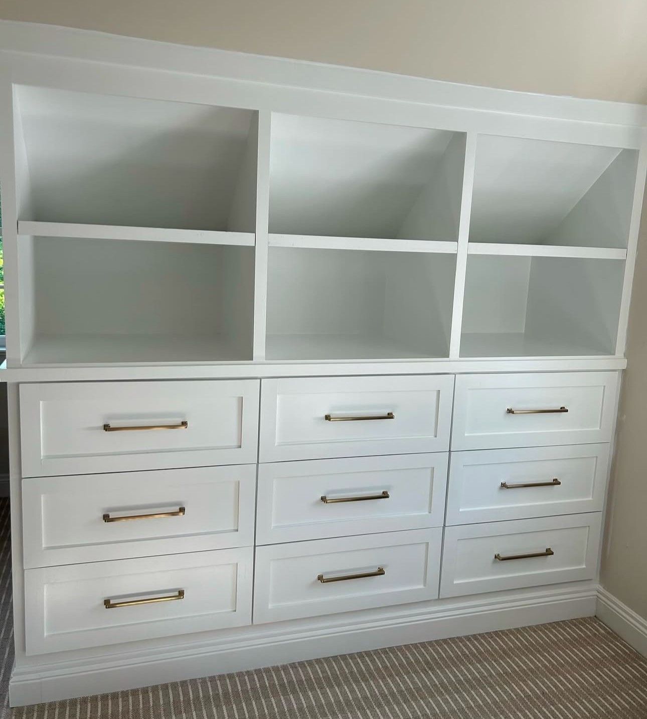 A white dresser with drawers and shelves in a room.