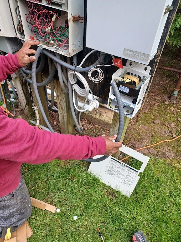 A man is working on an electrical box in the grass.