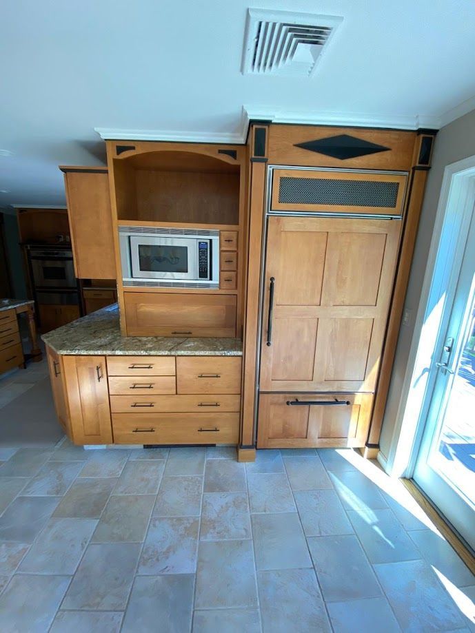 A kitchen with wooden cabinets , a microwave , and a refrigerator.