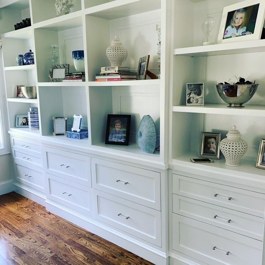 A room with a lot of white shelves and drawers