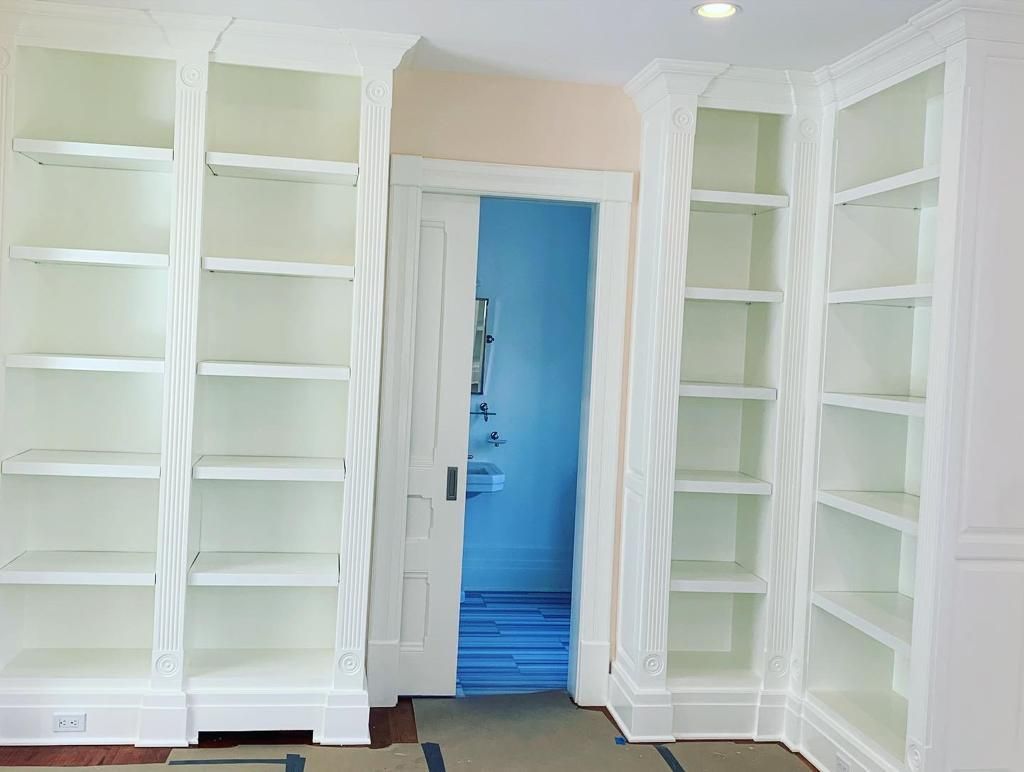 A room with white shelves and a blue door