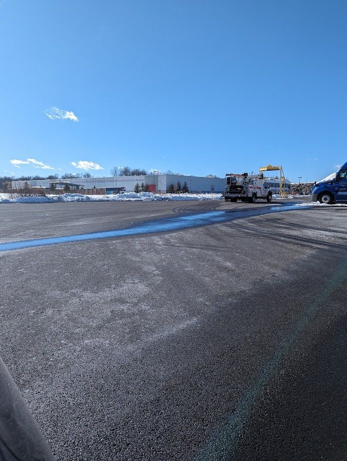 A blue truck is parked in a parking lot in front of a building.