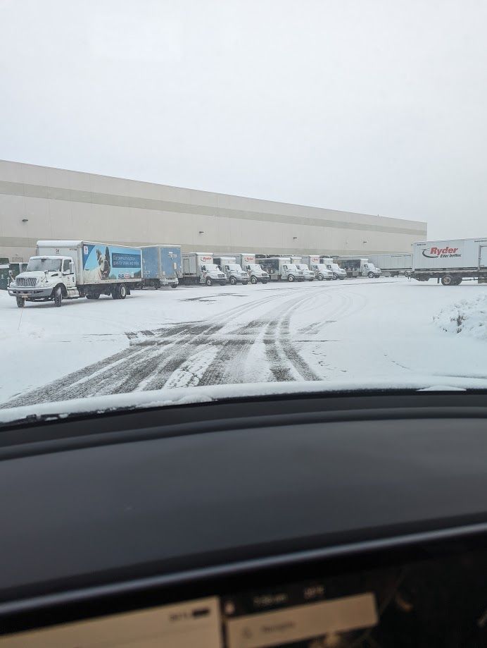 A row of trucks are parked in a snowy parking lot