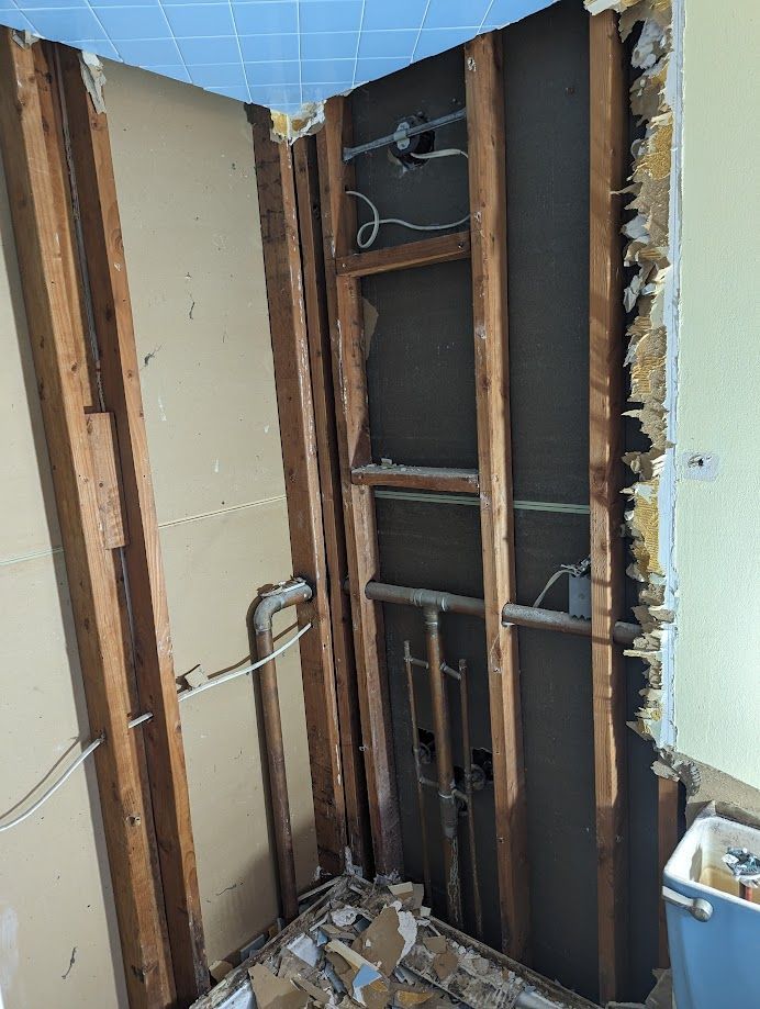 A bathroom with a hole in the wall and pipes coming out of it.