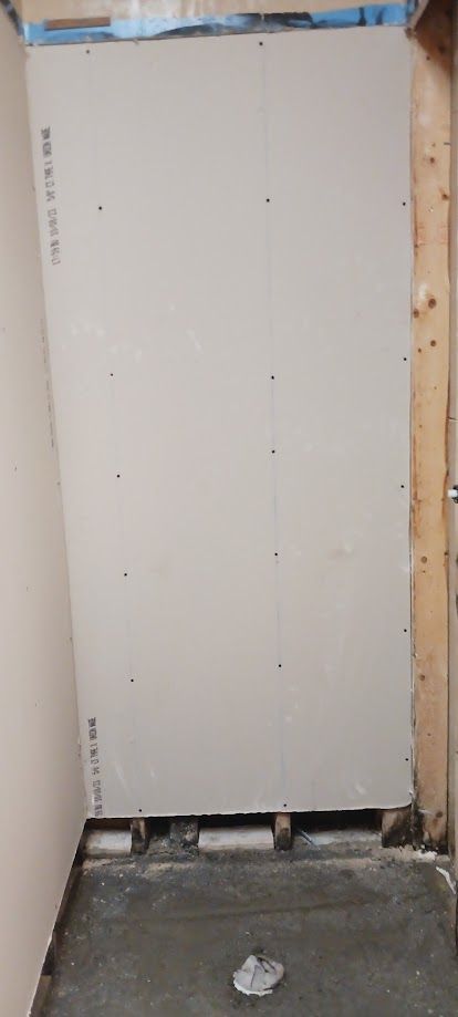 A large piece of drywall is sitting on top of a concrete floor in a room.