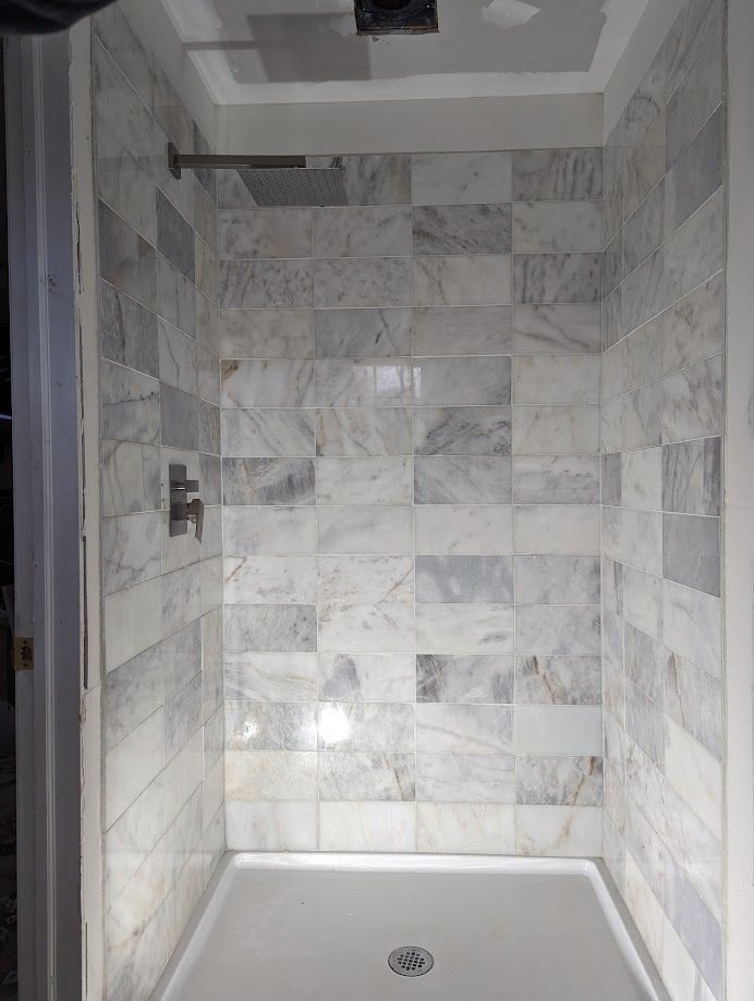 A shower stall with marble tiles and a shower head.