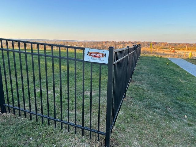 A black metal fence with a caution sign on it.