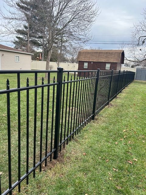 A black metal fence surrounds a lush green yard.