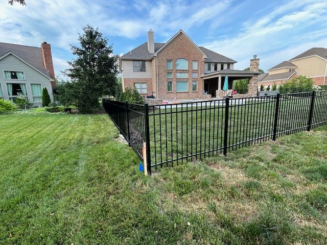 A large brick house with a black fence in front of it.