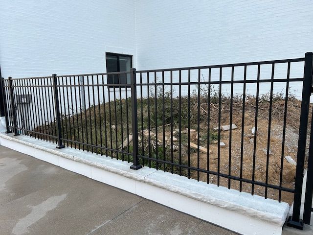 A black metal fence is surrounding a white building.