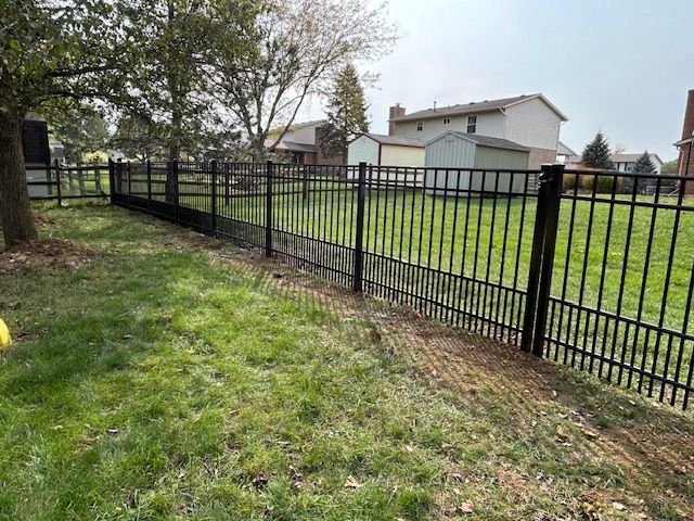 A black metal fence surrounds a lush green yard.