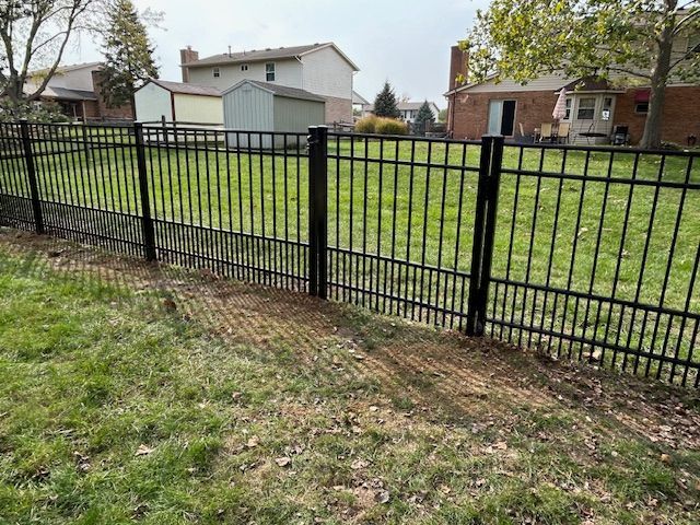 A black metal fence surrounds a lush green yard.