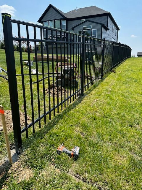 A black metal fence is being built in front of a house.