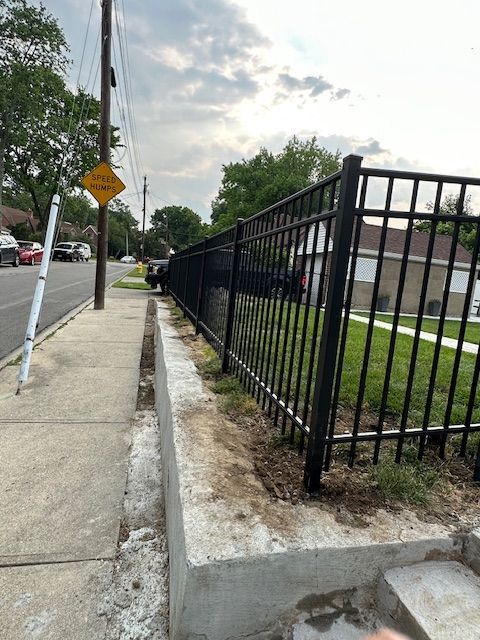 A fence is being built on the side of the road next to a sidewalk.