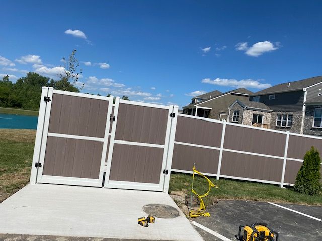 A brown and white fence is being built in front of a house.