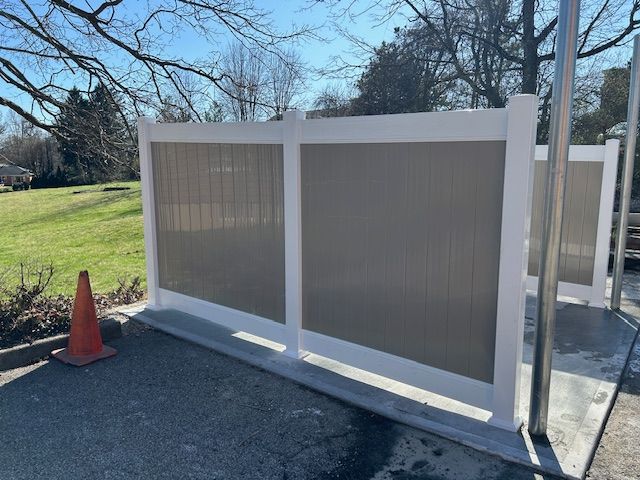 A white and brown fence with a traffic cone in front of it.
