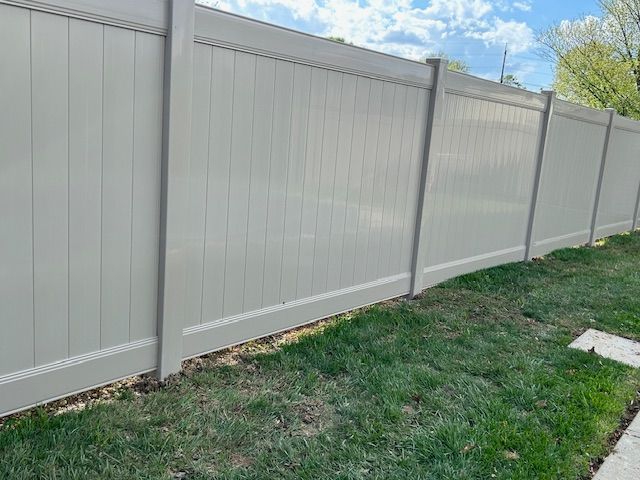 A white vinyl fence is sitting on top of a lush green lawn.