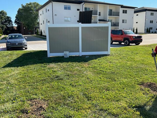 A white fence is sitting in the middle of a lush green field.