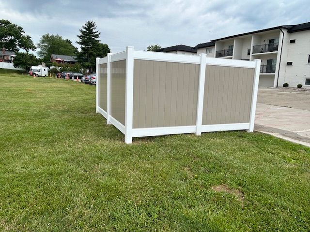 A brown and white fence is sitting in the middle of a lush green field.