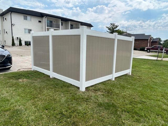 A white fence is sitting in the grass in front of a building.