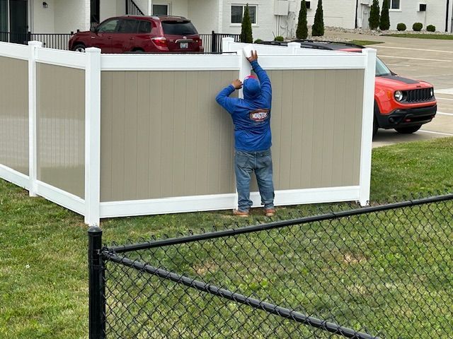 A man is standing next to a fence in a yard.