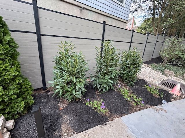 A fence with a lot of plants growing next to it