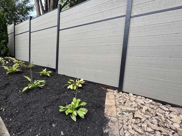 A fence is surrounded by plants and rocks in a garden.