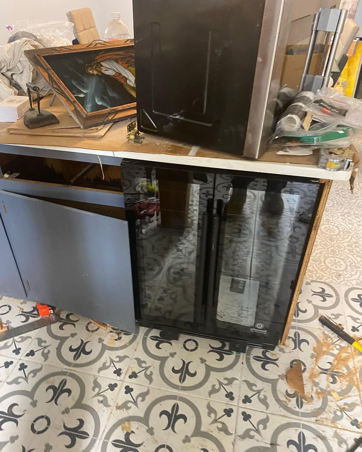 Kitchen cabinets under construction, gray and black units with exposed interior, and tiled flooring.