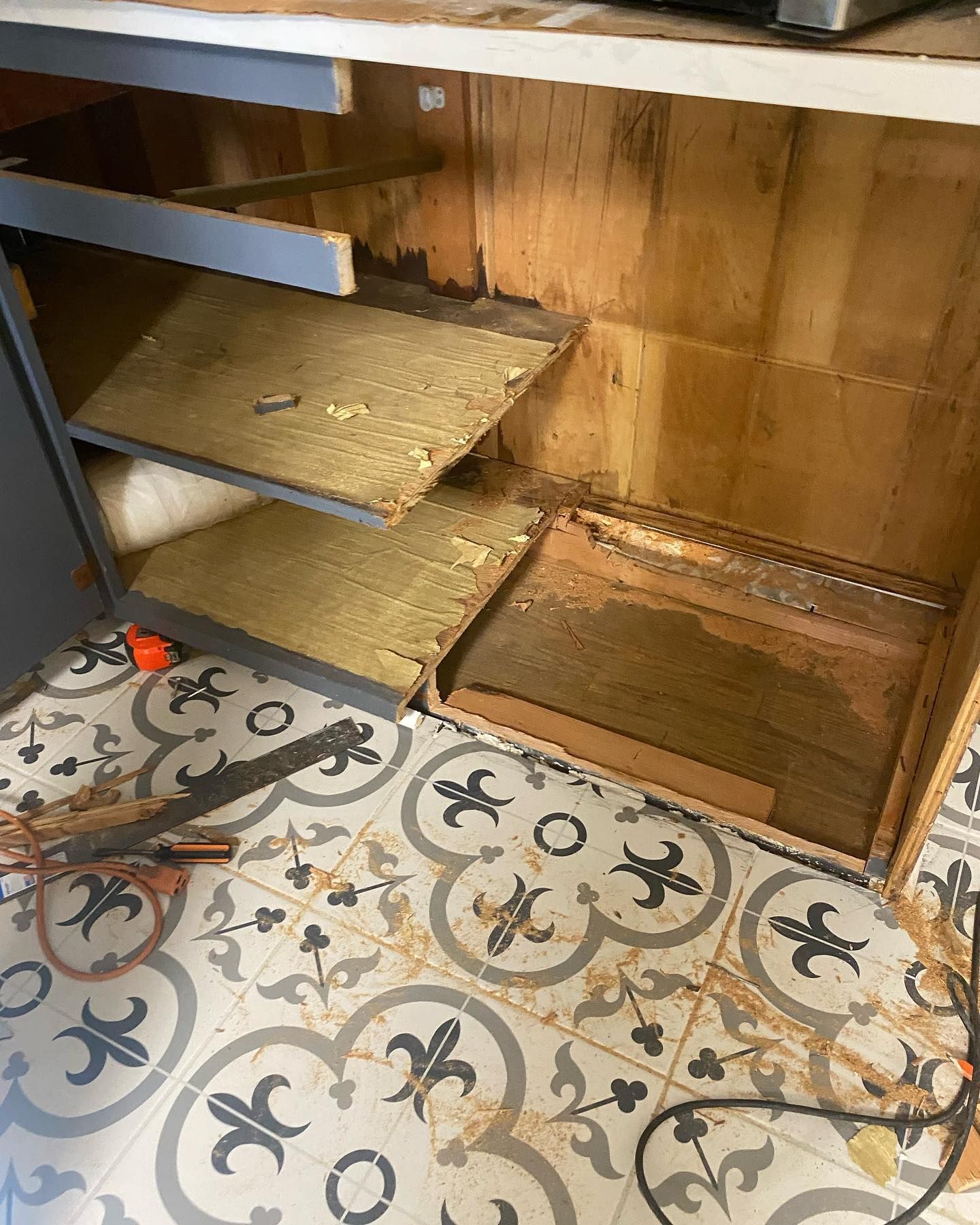 Damaged cabinet interior with broken shelves and visible water damage.