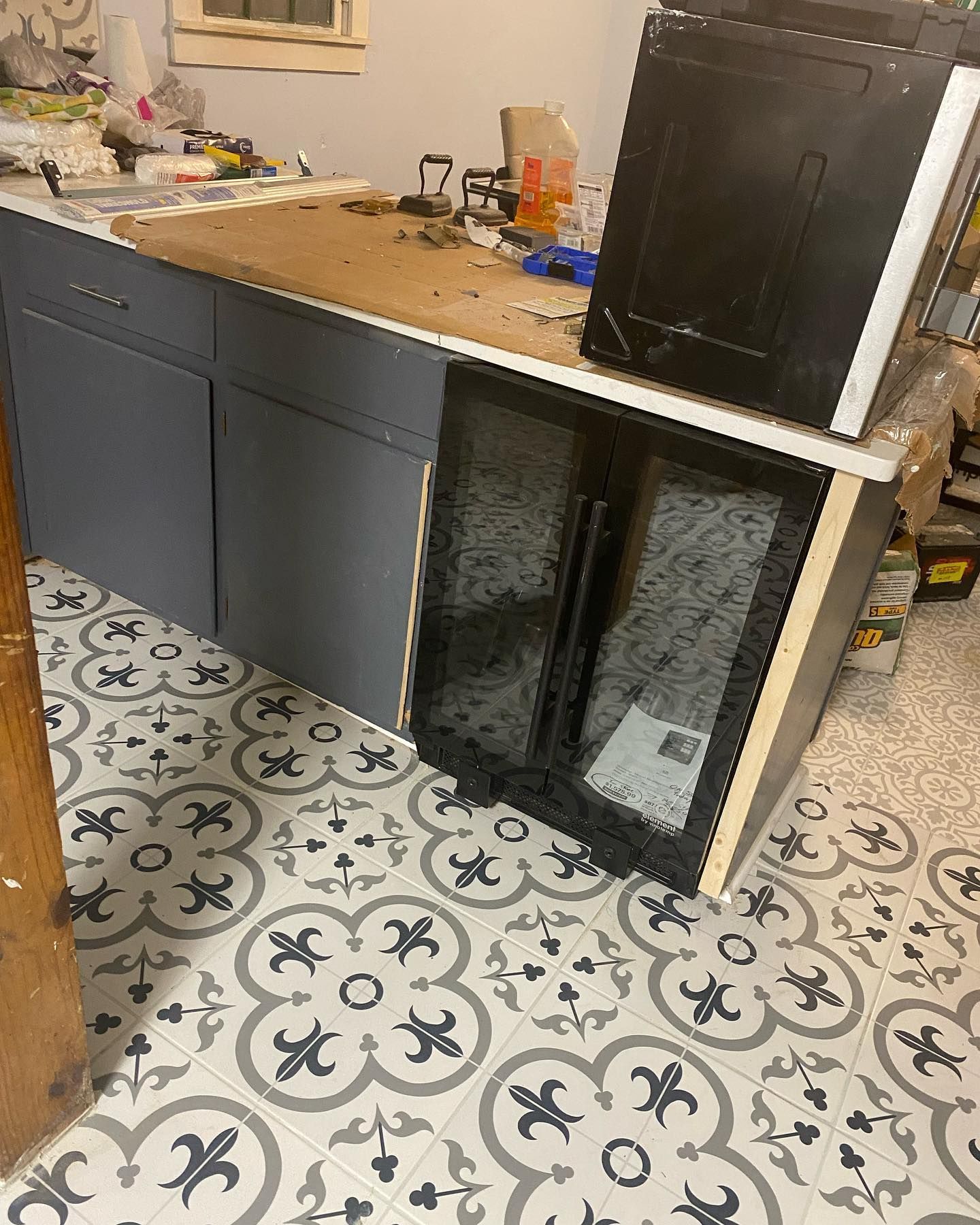 Cabinets, countertops, and a refrigerator on a patterned floor. A computer case sits on the counter.