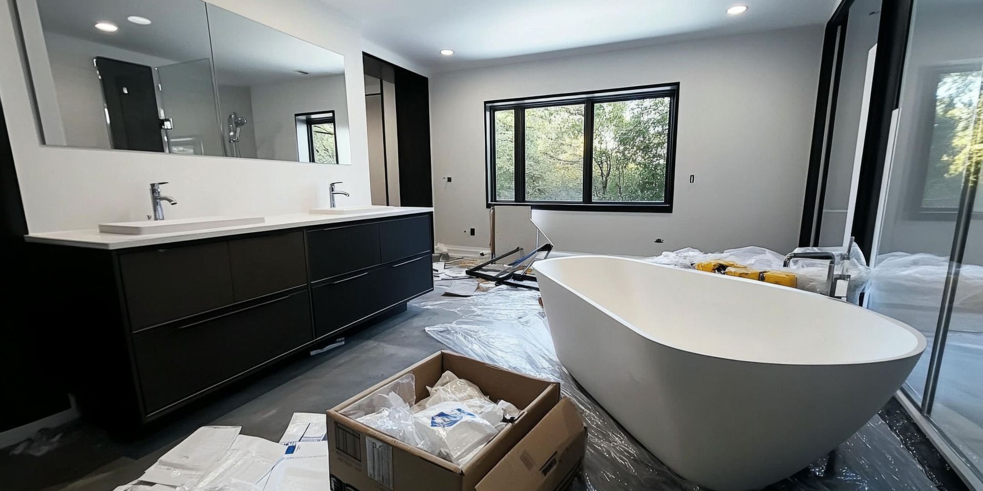 Bathroom with black vanity, white bathtub, and large window under construction.