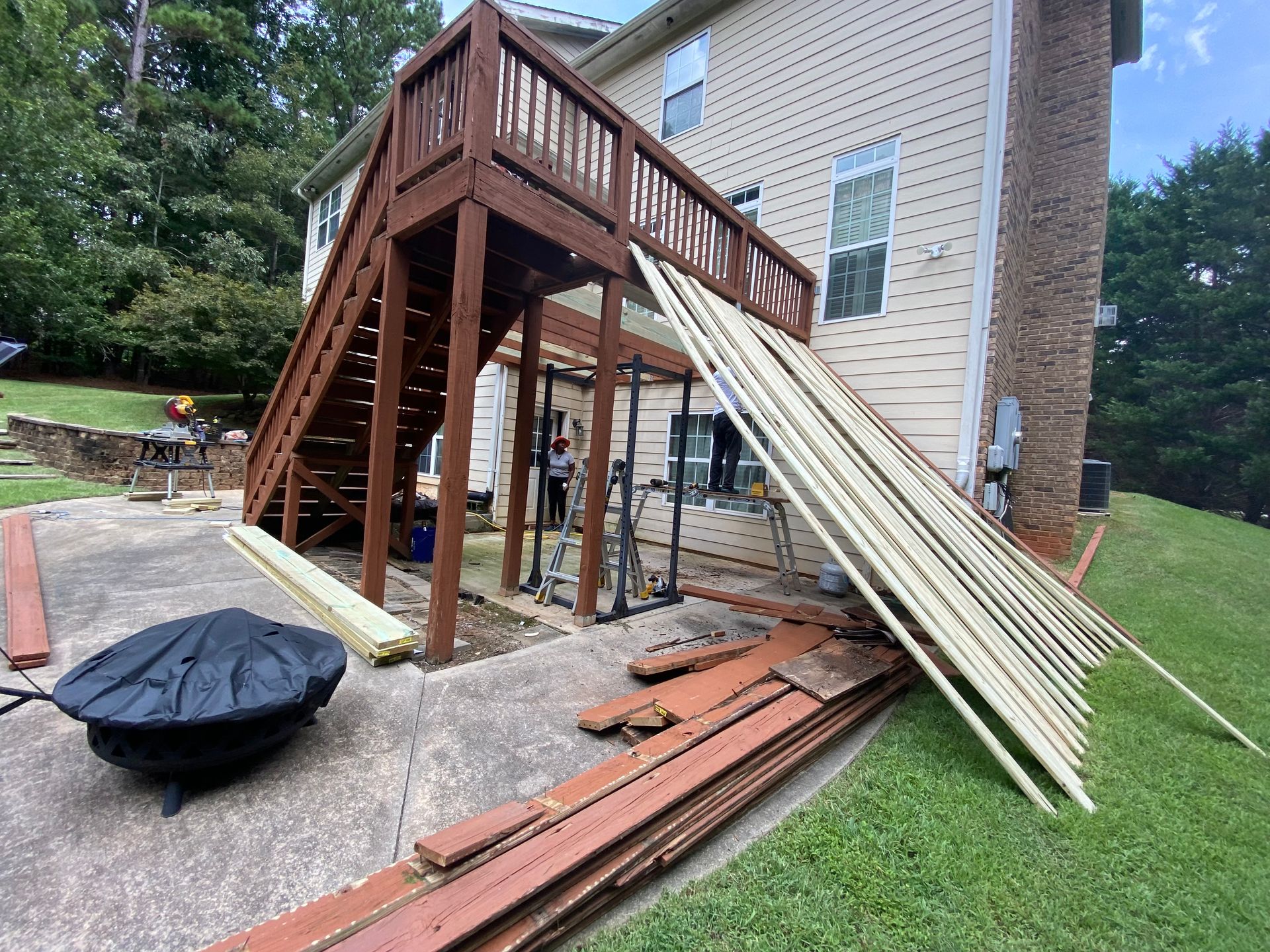 Backyard deck under construction; brown wood, beige house, new wood planks.