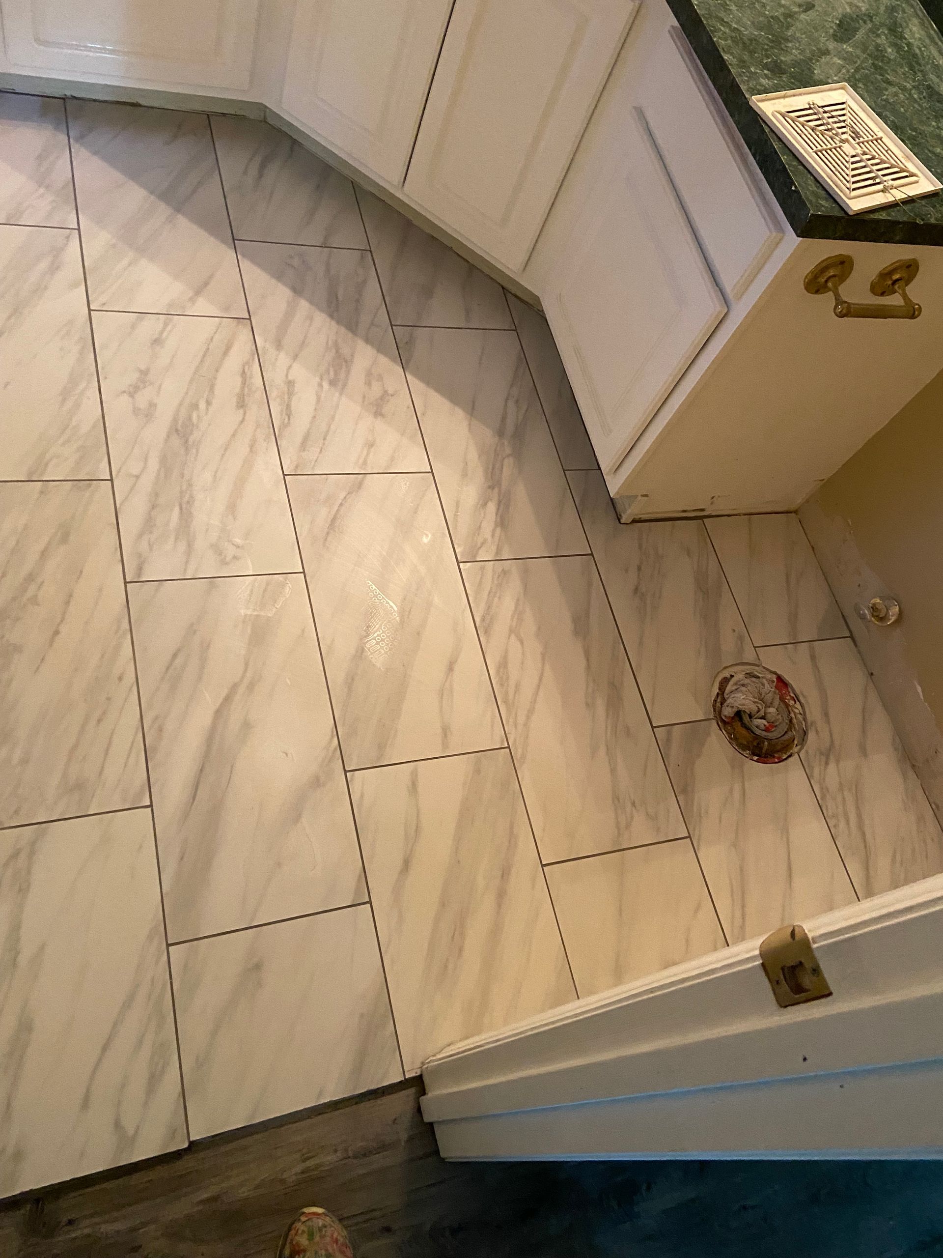 Kitchen with marble-patterned floor tiles. White cabinets and a dark countertop are visible.