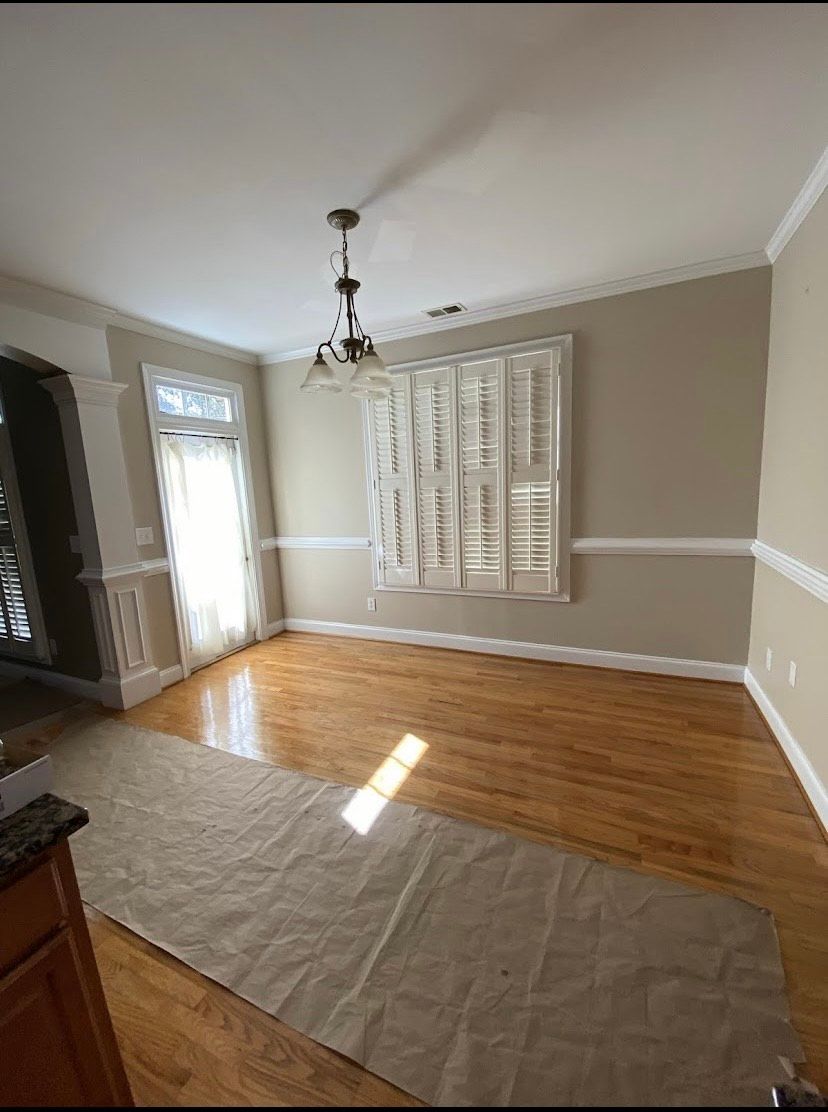 Dining room with hardwood floors, tan walls, white shutters, and a chandelier.