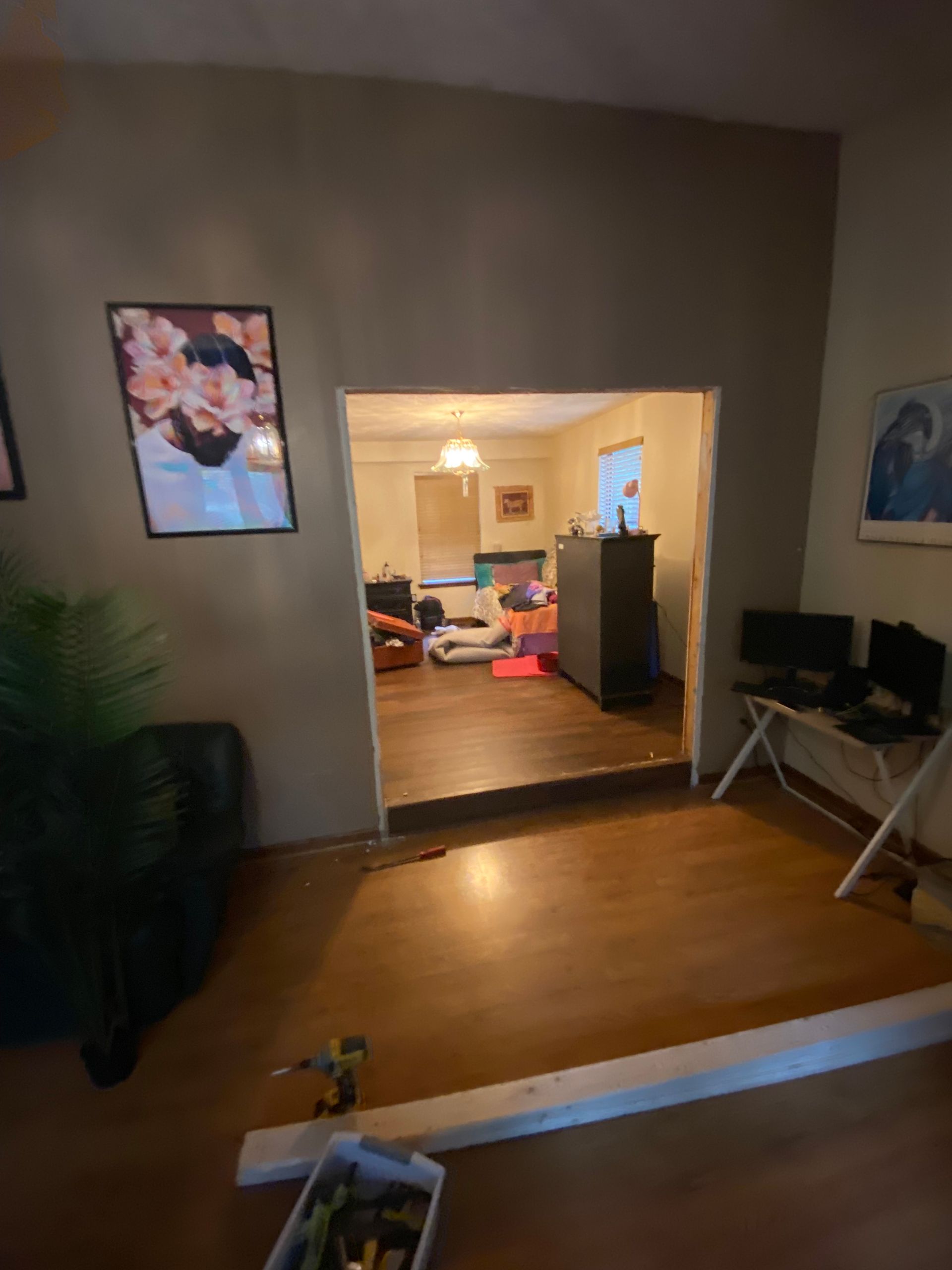 Interior view through an opening to a room with furniture, wood floors, and neutral walls.