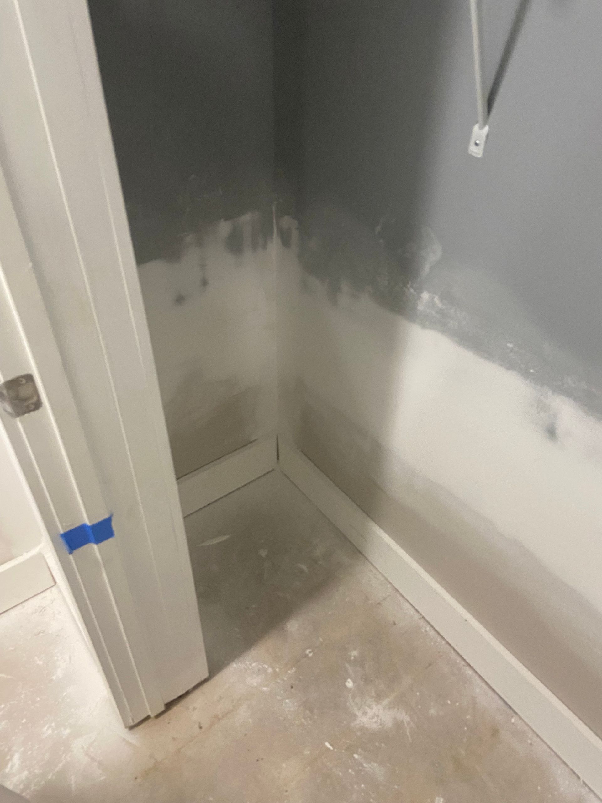 Corner of a room with white trim, unfinished walls (gray and white), and a doorway.