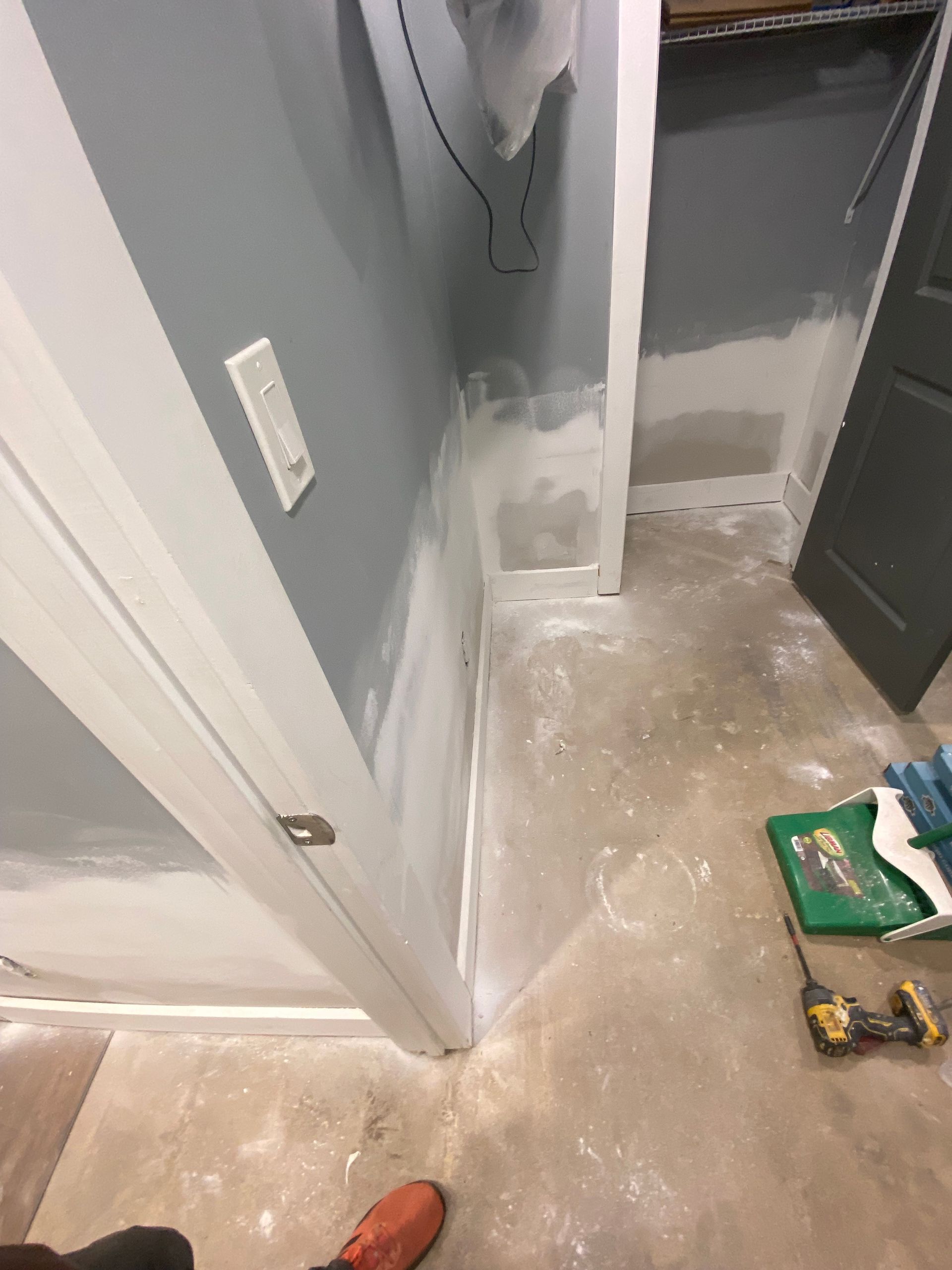 Renovated interior with painted walls, doorway, and unfinished concrete floor. Paint supplies are visible.