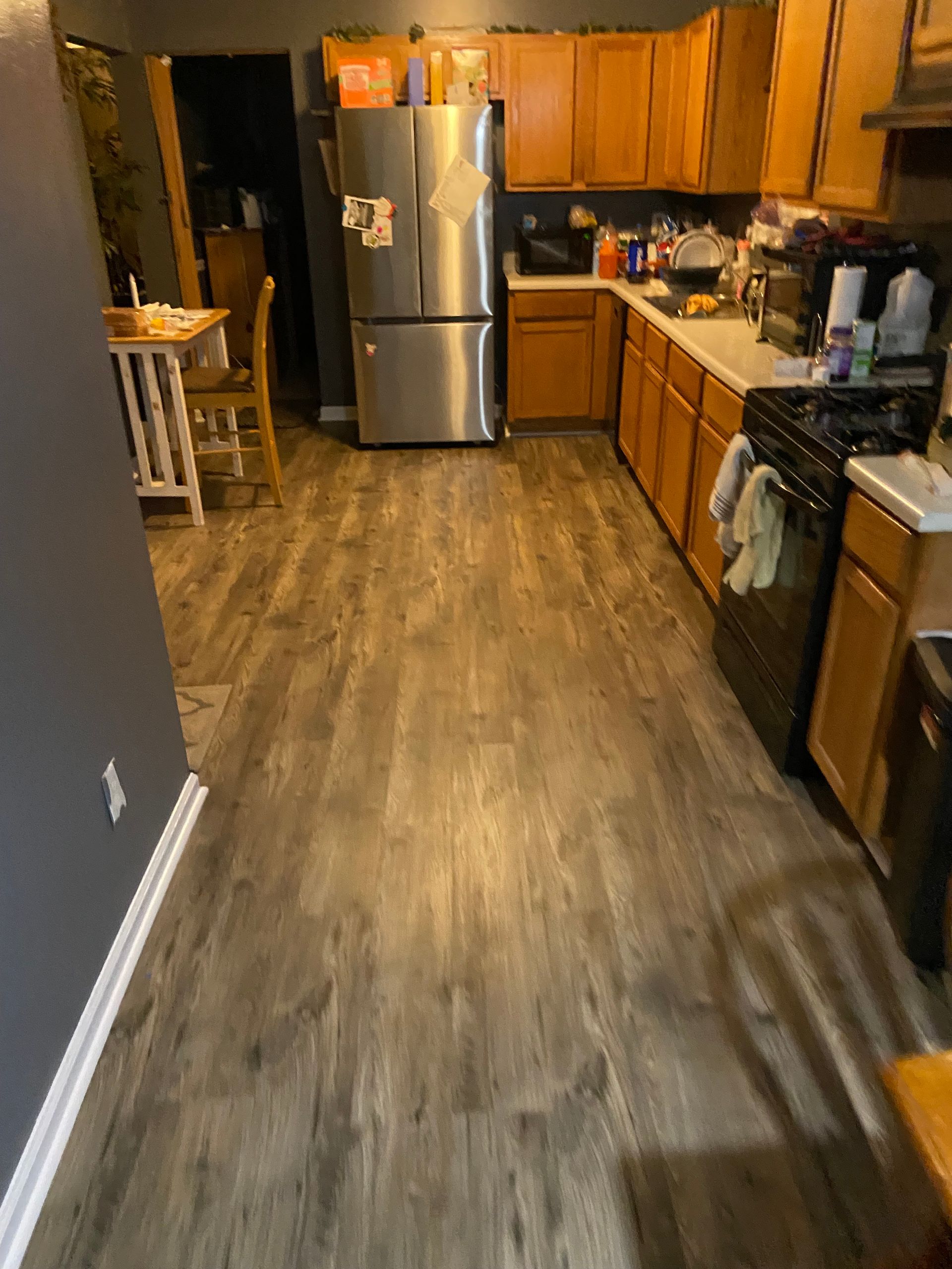 Kitchen with wood-look flooring, stainless steel appliances, and wood cabinets.