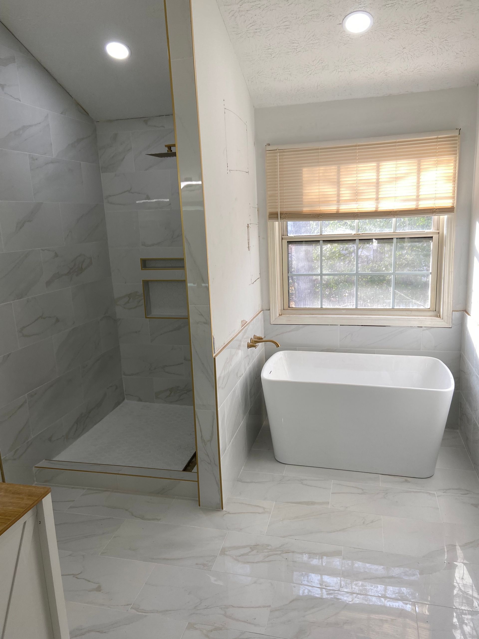 Newly renovated bathroom with a shower, bathtub, and window with a bamboo shade.
