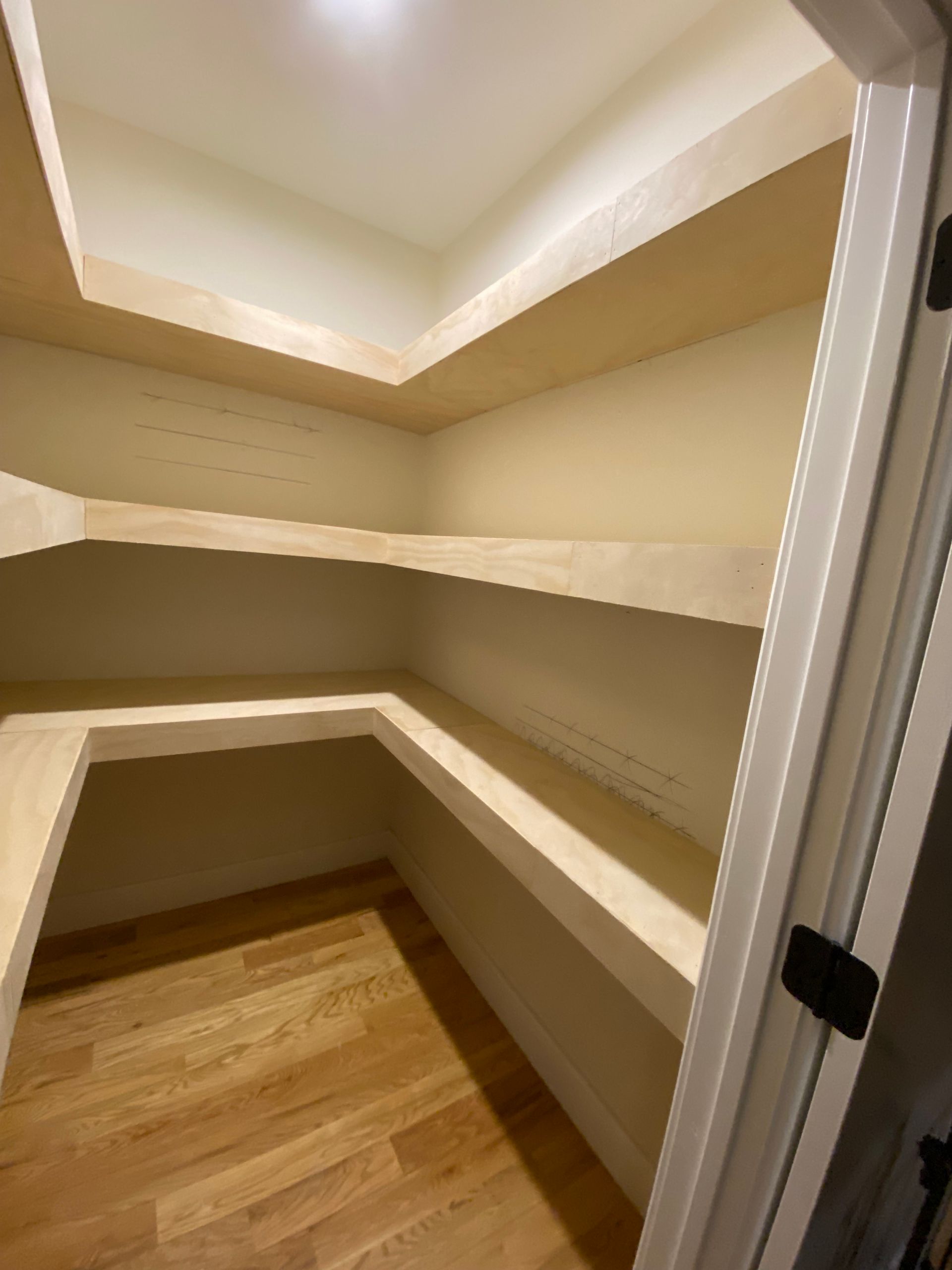 Empty pantry with wooden shelves and hardwood floor.