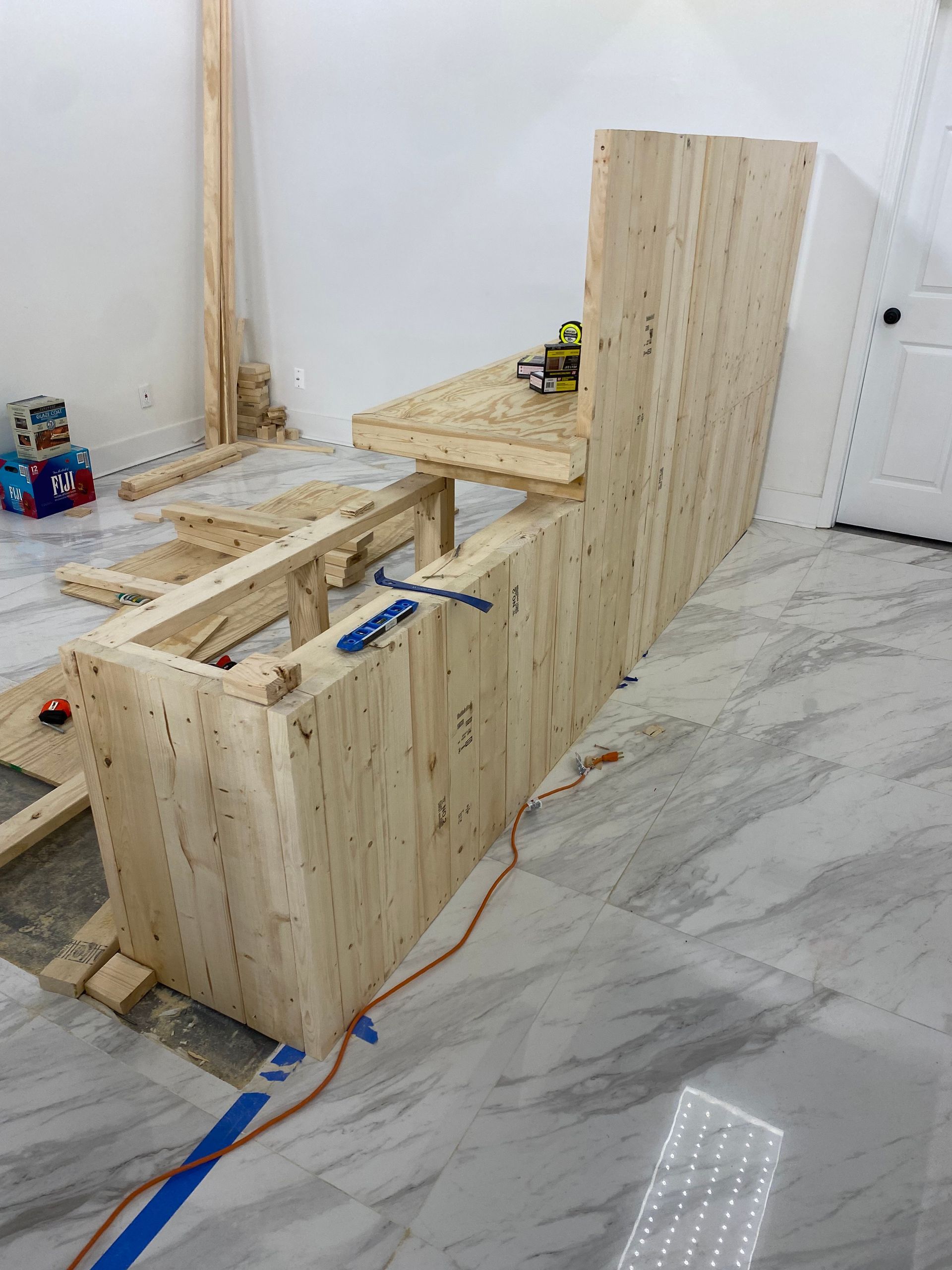 Wooden bar under construction against a white wall; tools and materials scattered around.