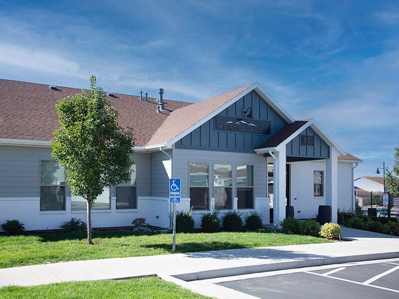 Exterior view of a modern apartment building with a handicapped parking sign and landscaping.