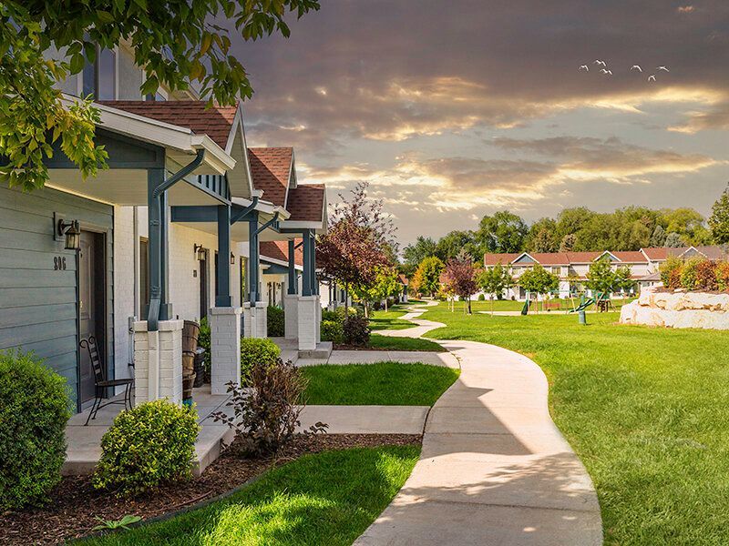Row of townhome-style apartment buildings with porches along a curved sidewalk.