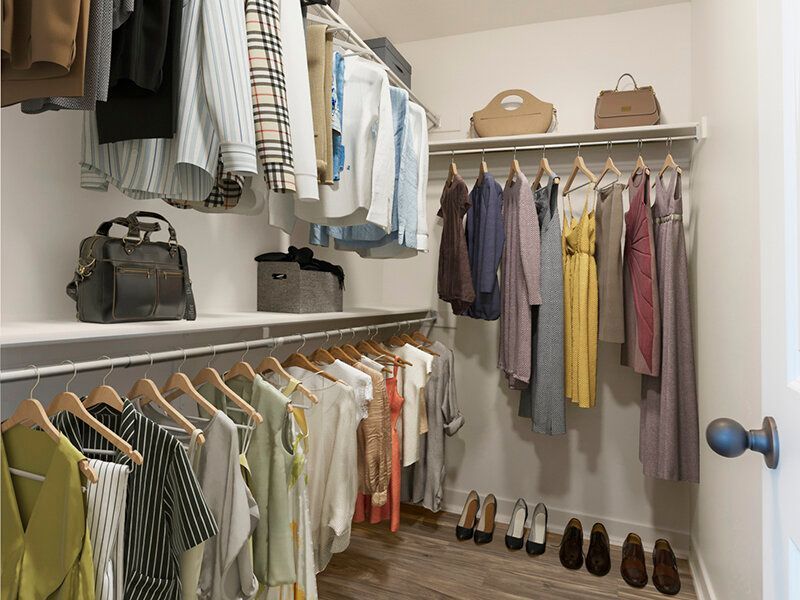 Walk-in closet in an apartment with clothes on racks, shelves, and shoes.