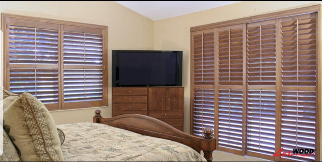 Bedroom with wood shutters on windows, a wooden dresser, and a bed.