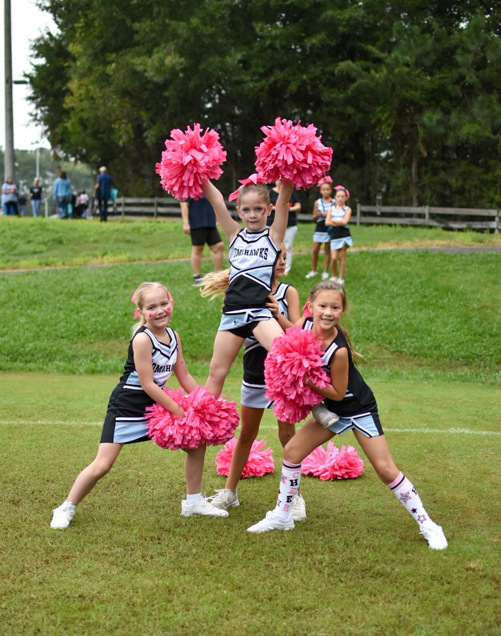 Cheerleader in red uniform performs a backbend on a green and red football field.