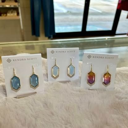 A pair of kendra scott earrings are sitting on a table.