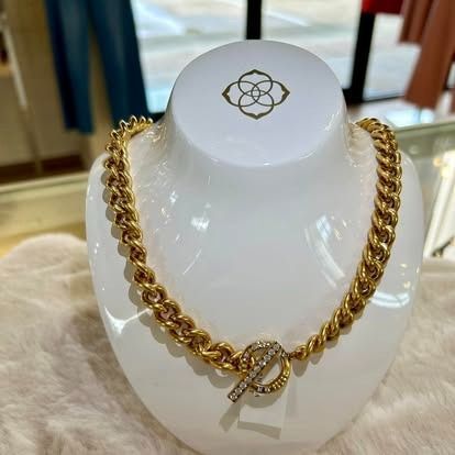 A gold necklace is on a white mannequin.